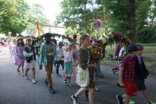 Bad Oldesloe: Kindervogelschießen: Am Bürgerpark, Blickrichtung Westen: Einzug auf den Exer: Festumzug Klaus-Groth-Schule, teils mit Blumenschmuck: im Hintergrund Bundesflagge und Jugendfreizeitstätte (JuZe): 13. Juli 2023