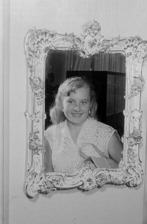 Portrait einer Frau im Spiegel mit einem Rahmen aus Meißner Porzellan im Messehaus Mädler-Passage auf der Leipziger Herbstmesse 1955