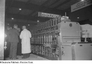 Messebesucher an einer Textilmaschine (Spindelmaschine)