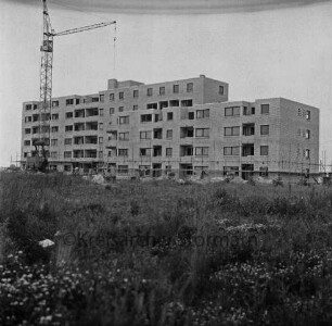 Fuchsberg / Im Hölk: Wohnblocks der Gemeinnützigen Wohnstätten Genossenschaft Bad Oldesloe: im Bau mit Gerüst: davor Baumaterial: hinten links Baukran: vorn verkrautete Wiese