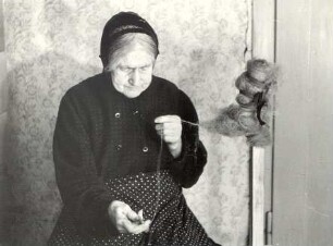 Frau beim Spinnen in Sprey : Handwerkstechniken - Spinnerei. Ort: Sprjowje / Sprey. Frau Hercowa spinnt mit einer Spindel.