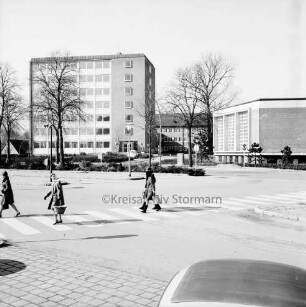 Erweiterungsbauten "Hochhaus" [später Gebäude B] und Kreistagssitzungssaal: dazwischen Hauptgebäude [später Gebäude A]: davor Parkplatz und Bäume: vorn Bahnhofsvorplatz mit Mommsenstraße: links vier Personen auf Zebrastreifen