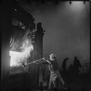 Mann beim Befeuern eines Schmelzofens im VEB Berliner Metallhütten- und Halbzeugwerke (BMHW) in Berlin Schöneweide. SW-Foto, 1967 © Kurt Schwarz.