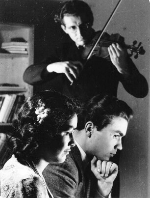 Hausmusik. Ein Mann spielt Violine. Man hört begeistert zu.