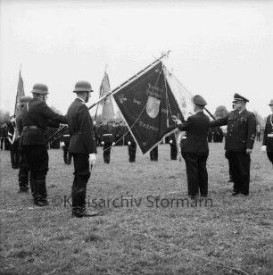 Meddewade: Freiwillige Feuerwehr Meddewade: Fahnenweihe: Festwiese: Fahnenträger mit der Meddewader Fahne und der Weihfahne des Amtes Bad Oldesloe-Land: Weihe durch Kreisbrandmeister Heinz Poschmann: dahinter Fahnenträger benachbarter Wehren: hinten angetretene Wehren und Zuschauer: 01.06.1974