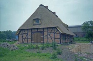 Schuhwiesenweg 2: Bauernhaus: nach Sanierung: mit Reetdach: Giebelseite ehemaliger Wirtschaftstrakt mit Fachwerk, Scheunentor