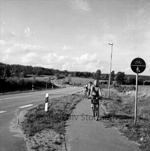 Radweg an Straße Weizenkoppel nach Rehhorst: Fahrradfahrerin: Verkehrsschild, Straßenlampe