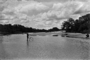Der Macloutsi-Fluss : Der Macloutsi-Fluss während der Regenzeit. Ein Mann vermisst die Breite des Flusses mit einem Messrad.