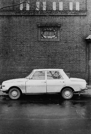 Parkender Wartburg vor Backsteingebäude