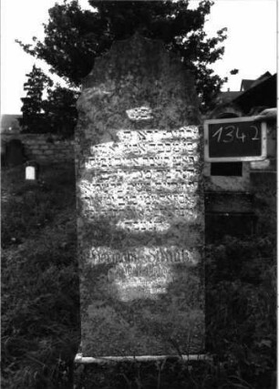 Grabstein 1342 (Index: 100104644) Material: Kunststein Zustand: leicht verwittert Maße HxBxT: 139x54x18 cm Beschreibung: aufgesockelte Stele mit Vorhangbogenabschluss (oder: mehrfach eingezogener Rundbogenabschluss): Grabstein 1342