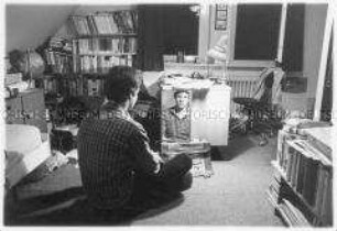 Jugendlicher sitzt in seinem Zimmer vor einem Spiegel (Altersgruppe 18-21)