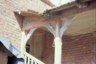 Hauseingang mit verzierten Holzsäulen, gesägten Kopfbändern