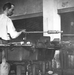 Ablegen der fertigen, noch glühenden Flasche auf dem Transporteur : Technikgeschichte | Technologie | Glasfabrikation | Flaschen | Hand-Fabrikation