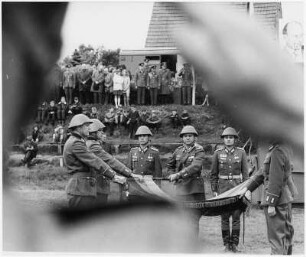 Waren (Müritz). Nationale Volksarmee - Landstreitkräfte. Öffentliche Vereidigung neu in das Panzerregiment 8 (PR-8) einberufener Wehrpflichtiger. Fahnenkommando (Mitte) und Schwursoldaten mit Hand an der entfalteten Truppenfahne