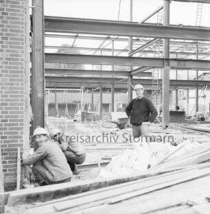 Firma Carl Hoffmann: Hindenburgstraße: Elektrohandel: Neubau: Aufbau des Stahlgerüsts: vorn und hinten Arbeiter zwischen Baumaterial: im Hintergrund Gebäude der Volkshochschule