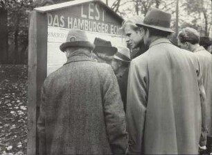 Hamburger Bürger lesen die neuen Verordnungen der Militärregierung an einer Informationstafel
