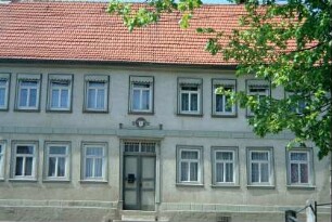 großes Wohnhaus mit langen Fensterreihen; Tür zur Straße