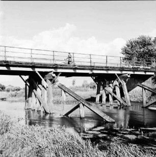 Trave: Holzbrücke in baufälligem Zustand: Fahrradfahrer auf Brücke: rechts Baum
