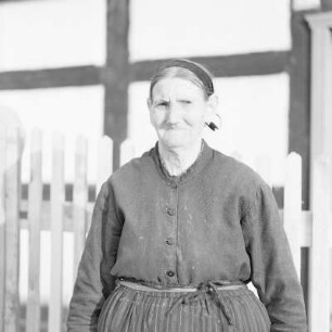 Ältere Frau in Spreewälder Alltagstracht vor ihrem Gehöft im Spreewald. : Starša žona we wšědnej Błótowskej drasće před swojim statokom w Błótach.