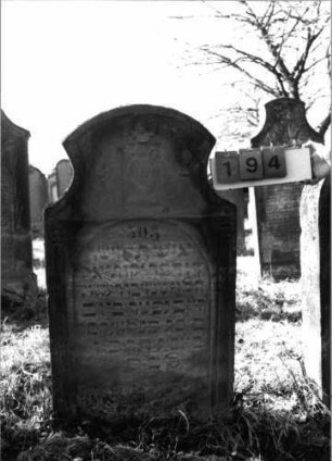 Grabstein 194 (Index: 100116358) Material: Sandstein Zustand: verwittert Maße HxBxT: 123x68x16 cm Beschreibung: Stele mit konkav eingezogenem Segmentbogenabschluß, eingetieftes Schriftfeld mit Rundbogenabschluß Symbolik: Levitenkanne, Blüte, Ranken: Grabstein 194 (Doppel von Nr 75560