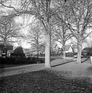 Dorfanger: Ehrenmal für die Kriegstoten beider Weltkriege: Bäume: hinten rechts Dorfstraße, links Teichstraße, Auto, Häuser