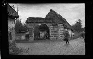 Metz-en-Couture (Dep. Pas-de-Calais, Frankreich): Blick auf ein Mauertor zu einem landwirtschaftlichen Anwesen (Distanzaufnahme)