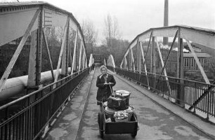 Essenbrücke : Bahren. Eine Frau fährt Essen in einem Handwagen über eine Brücke
