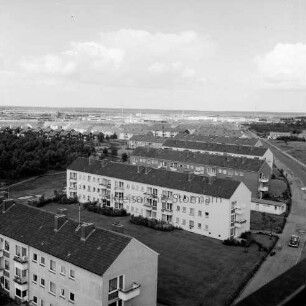 Gartenstadt Falkenberg: Blick vom Rathaus Richtung Nordosten: rechts Stonsdorfer Weg mit parkenden Pkws auf Seitenstreifen: in der Mitte Wohnblocks: dazwischen Grünflächen: links Wäldchen: dahinter Reihenhäuser und weitere Wohnblocks: im Hintergrund das Gewerbegebiet Stonsdorf