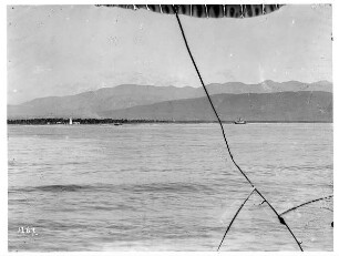 Bei Kingston, Jamaika. Blick von einem Kreuzfahrtschiff der Hapag auf Karibisches Meer mit Dampfer vor Küstenstreifen mit Leuchtturm gegen Bergwelt