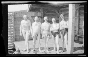 Gruppenbild mit 3 Männern mit Badehose und 2 nackten Männern in einer Badehütte