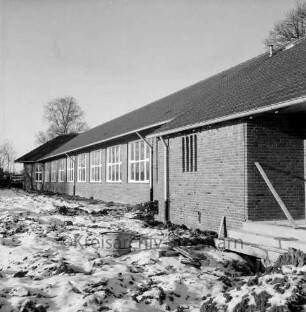 Volksschule: Schulkoppel: Neubau vor Fertigstellung: vorn rechts Turnhalle: vorn unbefestigtes Außengelände mit Baumaterial: Winter