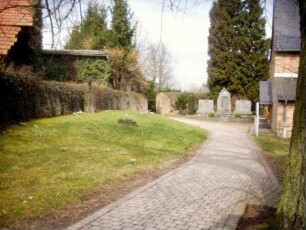 Kirchhof im Westen mit Kirchhofmauer (Wehrgang mit Steinbrüstung und Schießscharten abgetragen) in übersichtlichem Verlauf nach Norden