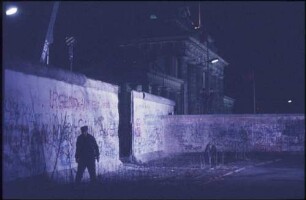 Ein Grenzsoldat läuft vor der Mauer bei der Maueröffnung am Brandenburger Tor