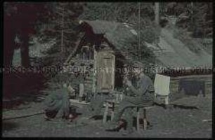 Gebirgsjäger vor einer Holzhütte