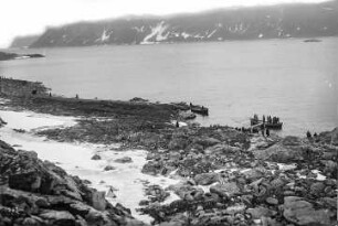 Spitzbergen (Norwegen). Touristen an der provisorischen Anlegestelle im Virgo-Hafen unter tiefhängenden Wolken