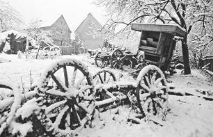 Schnee : Colditz. Verschneite Landschaft mit alten landwirtschaftlichen Arbeitsgeräten und Wagen im Vordergrund. Im Hintergrund ist ein Gehöft zu sehen