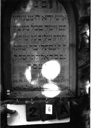 Grabstein 26 (Index: 100105456) Material: Muschelkalk, weiße Marmorplatte Zustand: gut Maße HxBxT: 104x58x27 cm Beschreibung: Stele, rustica, Rundbogenabschluß, Schriftplatte: Grabstein 26A