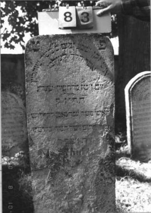 Grabstein 83 (Index: 99786940) Zustand: unteres Drittel stark verwittert Maße HxBxT: 115x44x13 cm Besonderheit: kulturhistorisch wertvoll / hist.-wiss. Gründe (Gemeindestellung): Grabstein 83