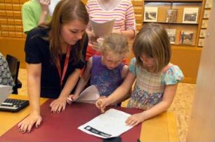 Kinder bei der "Bibliotheksrallye für Kinder" (Kinder lernen die Bibliothek spielerisch auf einer Rallye kennen. Die Maya-Zahlen weisen den Weg) im Serviceraum der Deutschen Fotothek