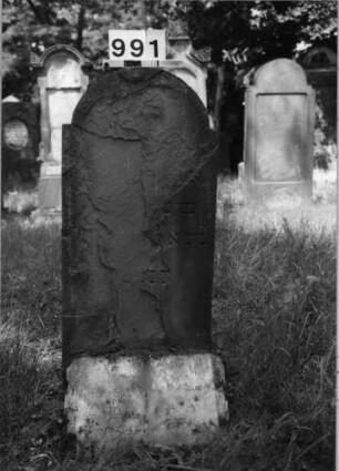Grabstein 991 (Index: 99630494) Material: Sandstein Zustand: stark abgeblättert-Stele Maße HxBxT: 108x48x6 cm Beschreibung: Stele mit eingezogenem Rundbogenabschluß Besonderheit: Zitat Psalm 116, 9: Grabstein 991
