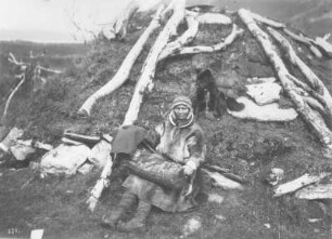 Bei Tromsø (Norwegen). Samenmutter mit Säugling und Hund vor ihrer Erdhütte