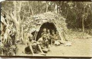 Mehrere Männer, Frauen und Kinder der Bagielli vor einer Hütte