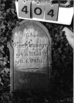 Grabstein 404 (Index: 99792056) Material: Sandstein Zustand: verwittert, Stele liegend Maße HxBxT: 51x30x15 cm Beschreibung: Stele, ausgezogener Spitzgiebelabschluß, Schriftfeld eingetieft Besonderheit: Kindergrab: Grabstein 404