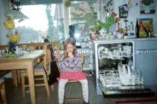 Schmollende Schwester in der Küche sitzend (Altersgruppe bis 14)