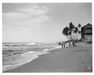 Colombo, Szene am Strand : Colombo, Sri Lanka. Tourist der Hapag mit Einheimischen und Kindern am Sandstrand vor einer Strandvilla und Palmen