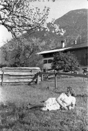 Rottach: blühender Baum und bayerisches Haus bei Rottach, mit Henny G. im Gras