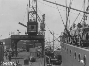 Hafenarbeit : Blick in den Hafen von Antwerpen mit Dampfschiff, Kran und Kai