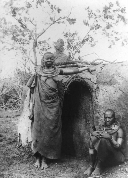 Maasai women with brass jewellery in front of their hut