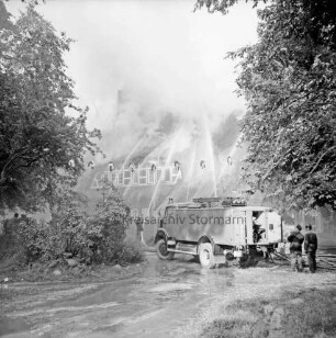 Kreiskinderheim Grande: Brand: im Vordergrund rechts Löschwagen der Feuerwehr mit Feuerwehrleuten: Löscharbeiten am brennenden Reetdach