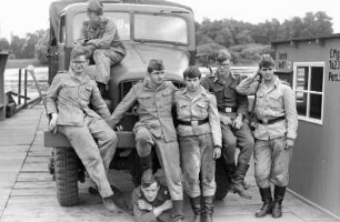 Gruppenbildnis NVA-Soldaten auf dem Flughafengelände in Dessau mit dem Fotografen Uwe Steinberg (links) : NVA-Soldaten vor einem Geländewagen auf dem Flughafengelände in Dessau, ehemaliger Flugplatz der Junkers-Werke